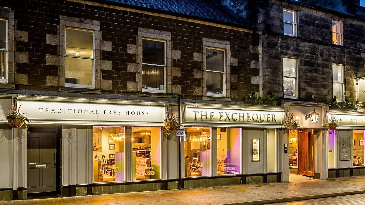 The front of The Exchequer in Kirkcaldy at dusk, its windows lit